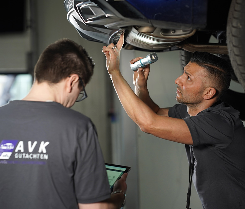 Kfz Gutachter Duisburg bei der Fahrzeugbewertung in der Werkstatt unter dem Auto