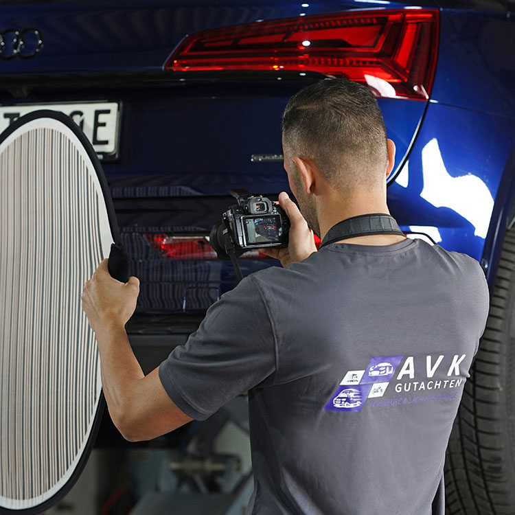 Kfz Gutachter in Duisburg fotografiert Fahrzeugschaden an einem blauen Audi mit professioneller Ausrüstung